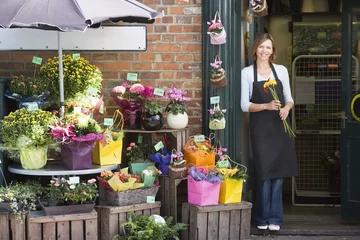 Rolgordijnen Bloemenwinkel Vrouw aan het werk bij bloemenwinkel glimlachend