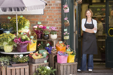 Vrouw aan het werk bij bloemenwinkel glimlachend