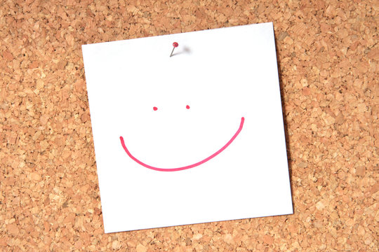 Smiley face pinned to a cork board