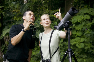 Pretty Woman with Binoculars and Man with Telescope in Jungle