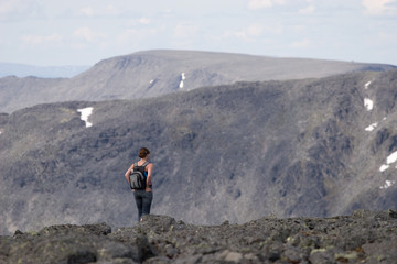 Girl atop of a rock overlooking the mountain panorama