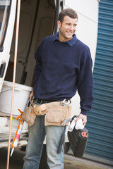 Plumber standing with van smiling