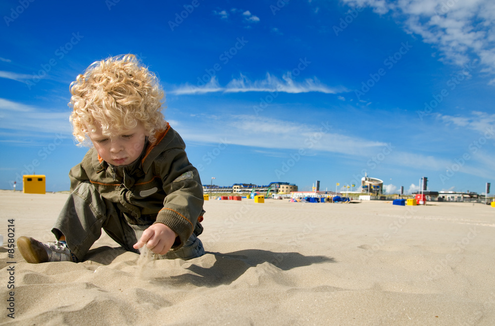 Wall mural cute boy playing with sand