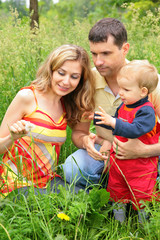 Fototapeta premium Parents with child sit in grass