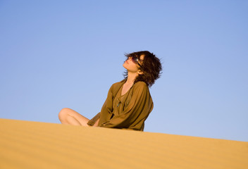 Fototapeta na wymiar Pretty woman sitting on the dune