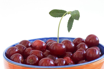 Ripe sweet cherry in a plate on white background