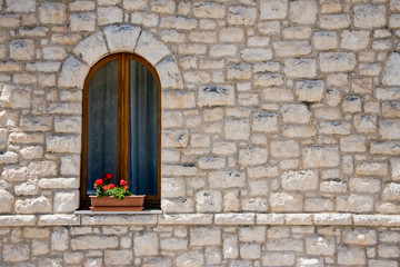 Muro di sassi con finestra e fiori