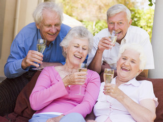 Two couples on patio drinking champagne and smiling