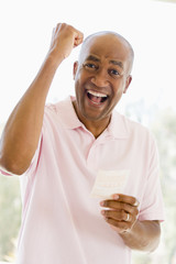 Man with winning lottery ticket excited and smiling
