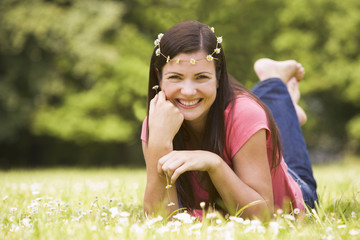 Naklejka na ściany i meble Woman lying outdoors with flowers smiling