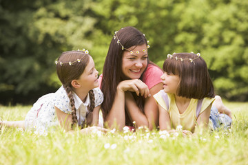 Mother and daughters lying outdoors with flowers smiling