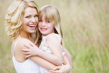 Mother holding daughter outdoors smiling