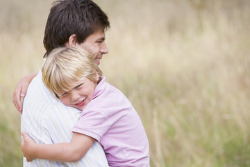 Fototapeta premium Father holding son outdoors smiling