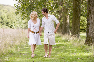Fototapeta premium Couple walking on path holding hands smiling