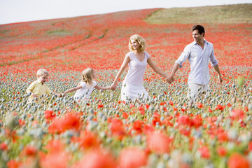 Family walking in poppy field holding hands smiling
