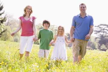 Family walking outdoors holding flower smiling