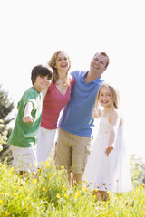 Family standing outdoors holding hands smiling