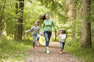 Fototapeta premium Mother and daughters skipping on path smiling