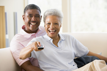 Obraz premium Couple in living room using remote control smiling