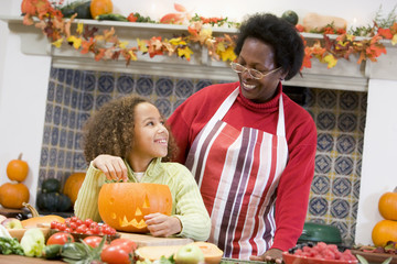 Grandmother and granddaughter making jack o lantern on Halloween
