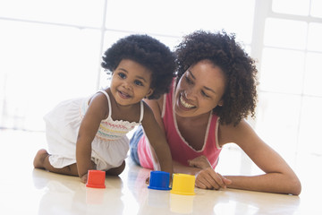 Mother and daughter indoors playing and smiling