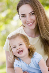 Mother holding daughter outdoors smiling