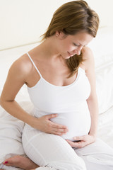 Fototapeta na wymiar Ciąży Kobieta siedzi w łóżku uśmiecha