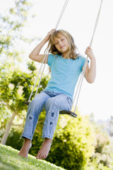 Young girl sitting on swing smiling