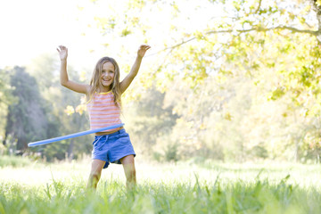 Young girl with hula hoop outdoors smiling - obrazy, fototapety, plakaty