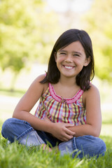 Fototapeta premium Young girl sitting outdoors smiling