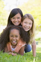 Three young girl friends piled up on top of each other outdoors