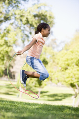 Young girl using skipping rope outdoors smiling