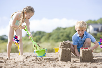 Brother and sister at beach making sand castles
