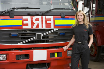 Portrait of a firefighter standing by a fire engine