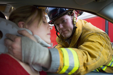 Firefighters helping an injured woman in a car