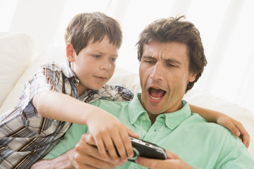 Young boy taking handheld game from unhappy man
