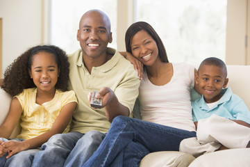 Family sitting in living room with remote control smiling
