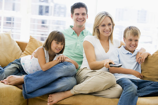 Family sitting in living room with remote control smiling