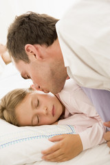 Fototapeta na wymiar Man waking young girl in bed with kiss