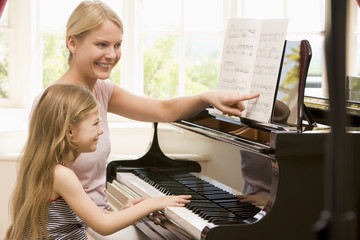 Woman and young girl playing piano and smiling © Monkey Business