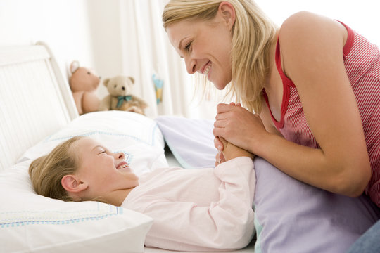 Woman with young girl in bed smiling