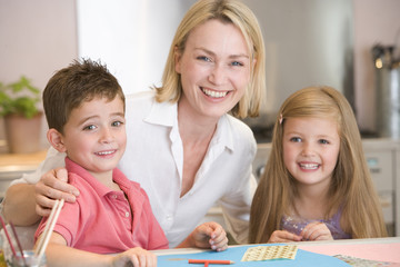 Woman and two young children in kitchen with art project smiling