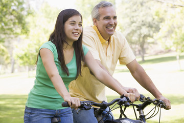 Obraz premium Man and girl on bikes outdoors smiling