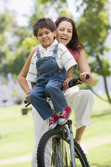 Woman and young boy on a bike outdoors smiling