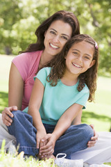 Fototapeta na wymiar Woman and young girl sitting outdoors smiling