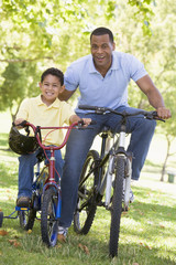 Obraz premium Man and young boy on bikes outdoors smiling