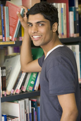 Male college student reaching for a library book