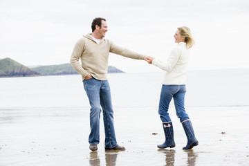 Couple walking on beach holding hands smiling