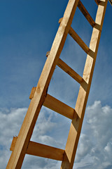 New wooden ladder on a background of the sky with clouds.