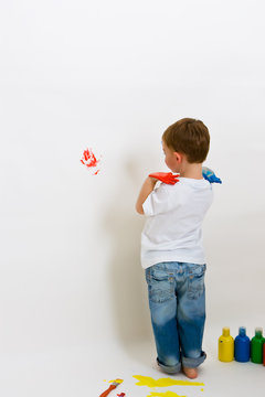 Child making hand prints on the wall with paint
